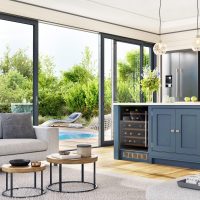 Modern Palm Desert kitchen and living room with large sliding glass windows opening to a backyard pool and garden. Modern Palm Desert kitchen and living room with large sliding glass windows opening to a backyard pool and garden.